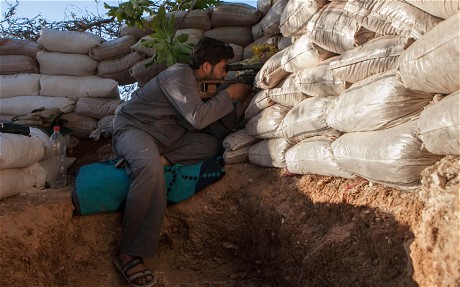 A rebel fighter holds position in a trench 100m from the regime-controlled military base of Wadi Deif (AFP)